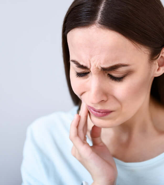 woman holding her jaw in pain