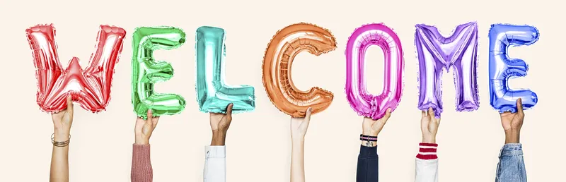 Multiple hands hold up multicolored balloon letters that say WELCOME against a peach background