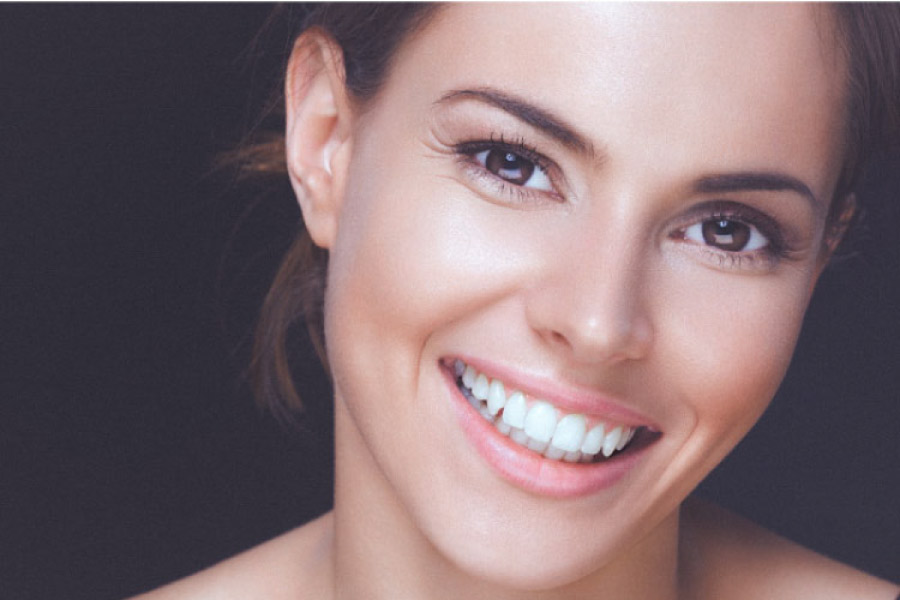 young woman smiles showing off her porcelain veneers