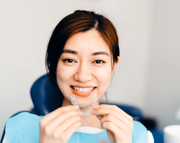 woman holding clear aligner