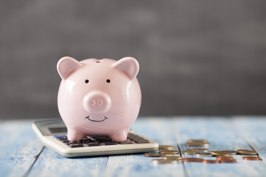 piggy bank and calculator to show savings from dental membership plan at Caring Smiles Dental