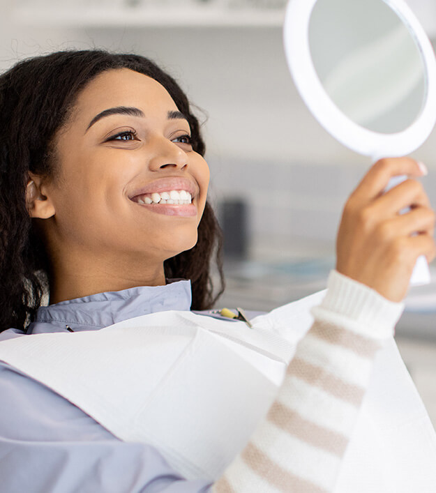woman examining her smile in a mirror