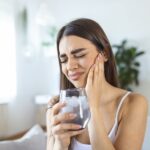 woman with tooth sensitivity or sensitive teeth after drinking ice water